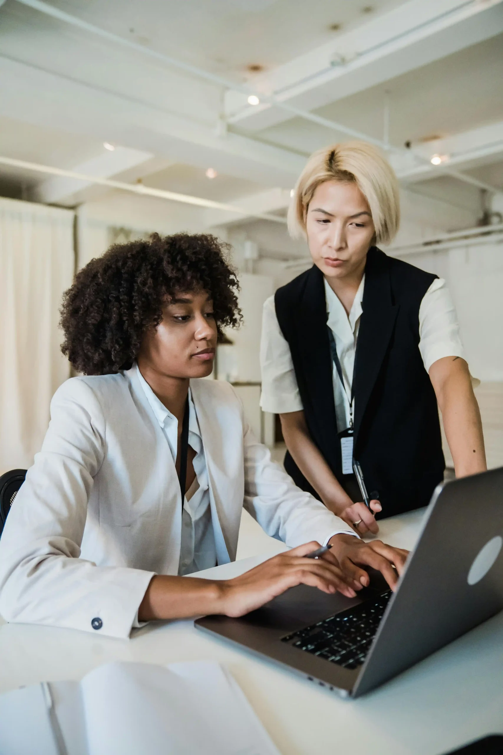 Two professionals collaborating over a laptop in a modern office.